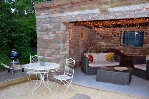 a patio with a table and chairs and a grill at Large Luxury Shepherds Hut with Hot Tub nr Bath in Bristol