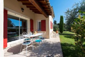 a patio with a table and chairs on the side of a house at Villa de 2 chambres avec piscine partagee jardin clos et wifi a Grillon in Grillon