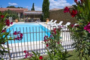 a swimming pool with white chairs and pink flowers at Villa de 2 chambres avec piscine partagee jardin clos et wifi a Grillon in Grillon
