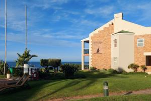 a large brick building with the ocean in the background at First Group Brookes Hill Suites in Summerstrand