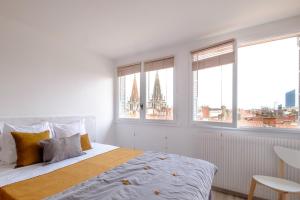 a white bedroom with a large bed and two windows at HONORÊ SUITE SAINT ANTOINE in Lyon