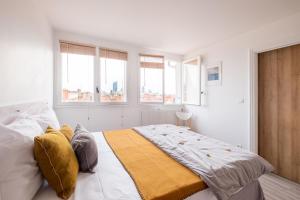 una camera da letto con un letto con pareti e finestre bianche di HONORÊ SUITE SAINT ANTOINE a Lione