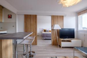 eine Küche und ein Wohnzimmer mit einem TV und einem Tisch in der Unterkunft HONORÊ SUITE SAINT ANTOINE in Lyon
