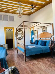 a bedroom with a canopy bed with blue pillows at Suítes Casa da Colônia in Paraty