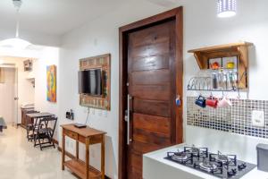 a kitchen with a stove and a wooden door at Praia de Geribá 100m - loft no corredor de acesso a praia in Búzios