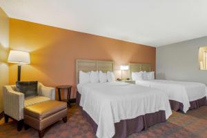 a hotel room with two beds and a chair at Best Western Pecos Inn in Artesia