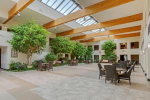 a large lobby with tables and chairs and trees at Best Western Pecos Inn in Artesia
