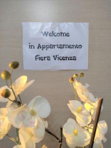 un cartel en una pared con flores blancas. en Appartamento Fiera Vicenza, en Vicenza