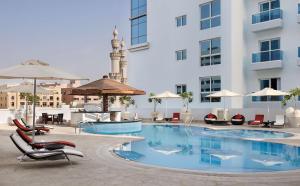 une piscine dans un hôtel avec des chaises et des parasols dans l'établissement Hyatt Place Dubai Al Rigga, à Dubaï