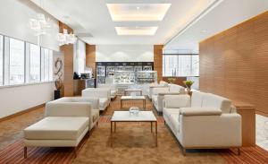 a waiting room with white couches and tables at Hyatt Place Dubai Baniyas Square in Dubai