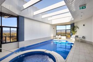 a swimming pool in a house with a ceiling with skylights at Rydges South Park Adelaide in Adelaide