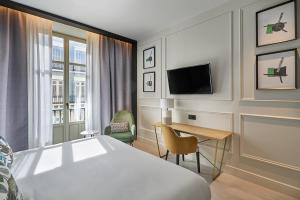 Habitación de hotel con cama, escritorio y TV. en Vincci Larios Diez, en Málaga