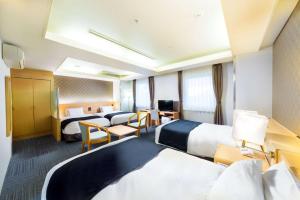 a hotel room with two beds and a desk at SureStay Plus Hotel by Best Western Shin-Osaka in Osaka