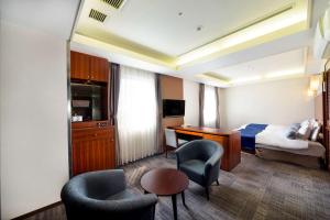 um quarto de hotel com uma cama, uma secretária e cadeiras em SureStay Plus Hotel by Best Western Shin-Osaka em Osaka