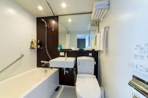 Baño pequeño con aseo y lavamanos en SureStay Plus Hotel by Best Western Shin-Osaka, en Osaka