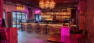 un bar con iluminación rosa y taburetes en un restaurante en The Waterside Bar, Rooms & Restaurant en Mánchester