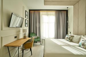 a bedroom with a bed and a desk and a window at Vincci Larios Diez in Málaga