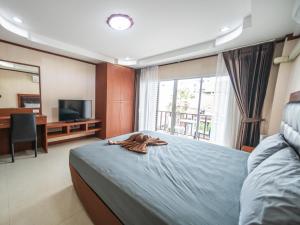 a bedroom with a bed and a tv and a window at Shiba Guesthouse in Pattaya South