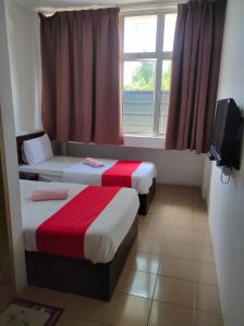 two beds in a room with a window and a tv at Hotel Star Inn in Teluk Intan