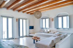 a living room with a large white couch and windows at Mystic Villas Koufonisi in Koufonisia