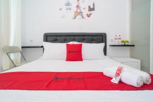 1 cama con almohadas rojas y blancas y manta roja en RedDoorz Syariah At Winong Nganjuk, en Nganjuk