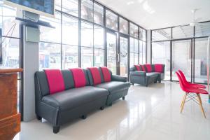 una sala de espera con 2 sofás de cuero y sillas rojas en RedDoorz Syariah At Winong Nganjuk, en Nganjuk