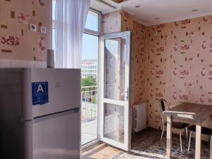 a kitchen with a refrigerator and a table and a window at Plaza Apartments in Bishkek