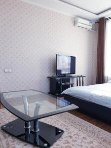 - un salon avec une table en verre et une télévision dans l'établissement Plaza Apartments, à Bishkek