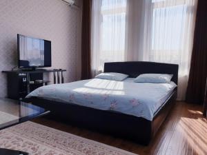 a bedroom with a bed and a flat screen tv at Plaza Apartments in Bishkek