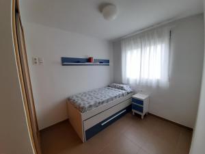 um pequeno quarto com uma cama e uma janela em Blaumar em Piles