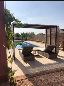 a patio with two chairs and a table next to a pool at Holiday home HDA Golf Resort - HK 0011 B - Villa con picina privada in Fuente Alamo