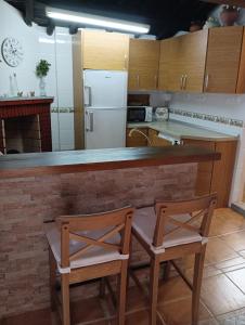 a kitchen with two chairs and a counter with a refrigerator at Casa rural TIO PEDRITO in Robledillo