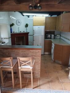 eine Küche mit einer Theke und 2 Stühlen darin in der Unterkunft Casa rural TIO PEDRITO in Robledillo