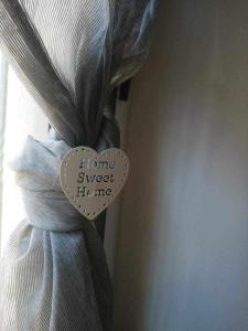 una etiqueta con forma de corazón en una cortina atada a una ventana en Los ojos de Norah boutique, en Mora de Rubielos