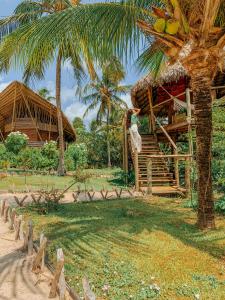 a resort with a palm tree and a hut at Villa Sabiá - Eco Bungalows in Prea