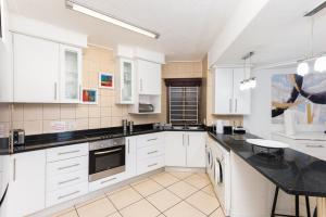 a kitchen with white cabinets and a black counter top at Alomsee 3 in Ballito