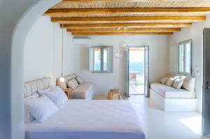 Mystic Villas Koufonisi في كوفونيسيا: غرفة معيشة بيضاء مع سرير وأريكة