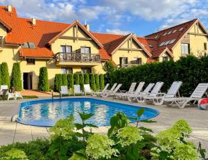 a swimming pool in front of a house with lounge chairs at Hotel Santa Monica in Mikołajki