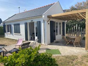 ein kleines weißes Häuschen mit Stühlen und einem Tisch in der Unterkunft Maison de vacances en bordure de mer ! in Batz-sur-Mer