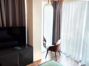 a living room with a television and a chair in front of a window at La Brisa Boutique Hotel in Dhërmi