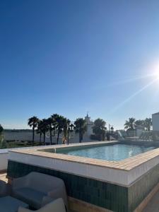 a swimming pool with chairs and palm trees at Hotel La Malvasía in El Rocío