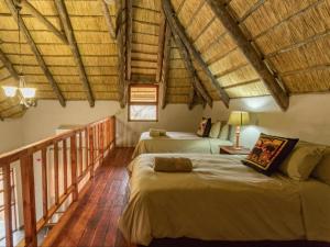 een slaapkamer met 2 bedden in een kamer met houten plafonds bij KaMsholo Bushveld Safaris 