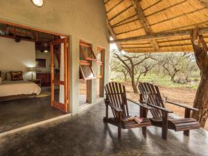 2 sedie e un tavolo in vetro in una camera da letto di KaMsholo Bushveld Safaris 