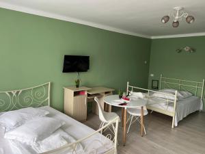 a bedroom with two beds and a table and a tv at Premont Studios Ghimbav in Ghimbav