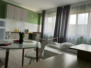 a room with a table and a bed and a kitchen at Premont Studios Ghimbav in Ghimbav