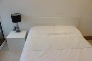 a bedroom with a white bed and a night stand at Luxury Canary Wharf 2 Bed Apartment With Panoramic Views in London