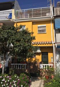 una casa amarilla con un árbol y flores en Apartamentos MásBambú, en Málaga