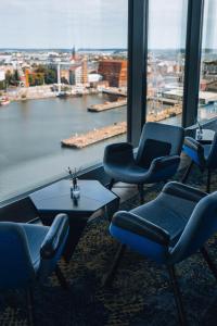 um quarto com cadeiras, uma mesa e uma grande janela em Clarion Hotel Helsinki em Helsinque