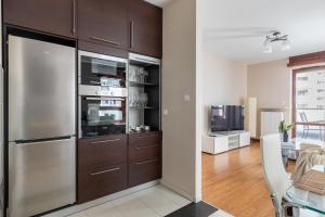 a kitchen with stainless steel appliances and a dining room at P&O Giełdowa Serviced Apartments in Warsaw