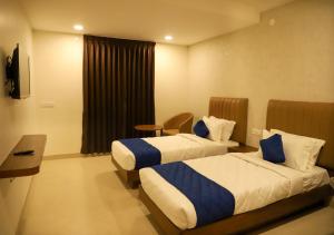 a hotel room with two beds and a window at Admira Residency in Coimbatore